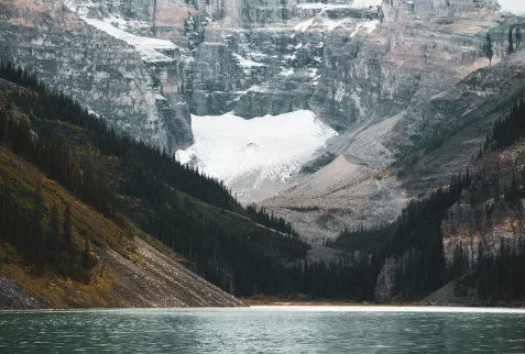 Stunning glacial lake surrounded by rugged snow-capped peaks and coniferous forests in the Canadian Rockies.